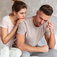 Lovely couple sitting on bed while woman calm down her boyfriend which upset
