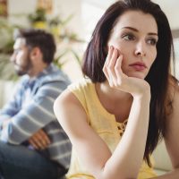 Upset couple ignoring each other on sofa in living room